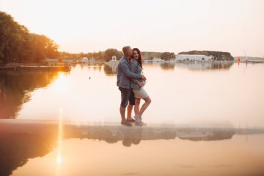 Aile günbatımında nehir kenarında duran bir bebek bekliyor.