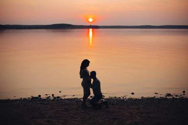 Hermosa foto del marido abrazando su vientre esposas contra el mar . — Foto de Stock