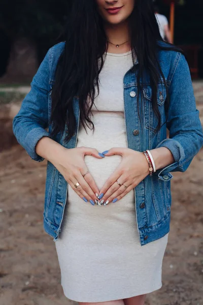 Femeia elegantă în blugi jachetă care ține palmele pe burtă . — Fotografie, imagine de stoc