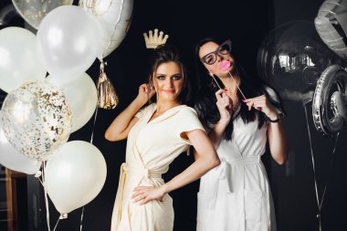 İki genç bayan aksesuarları tutarak ve kameraya poz.