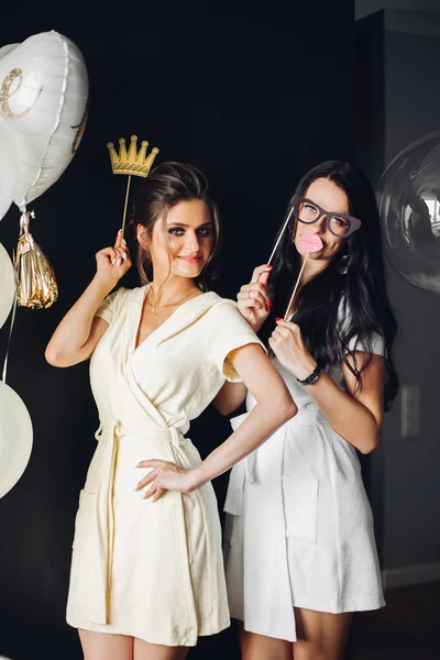 Duas jovens senhoras segurando acessórios e posando na câmera . — Fotografia de Stock