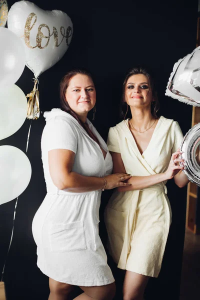 Dos señoritas sosteniendo accesorios y posando en la cámara . — Foto de Stock