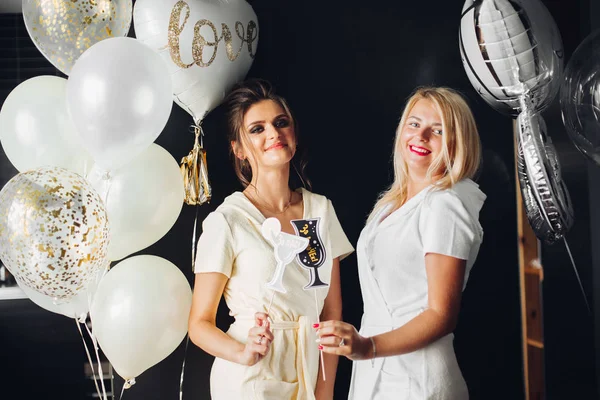 Deux jeunes femmes tenant des accessoires et posant à la caméra . — Photo