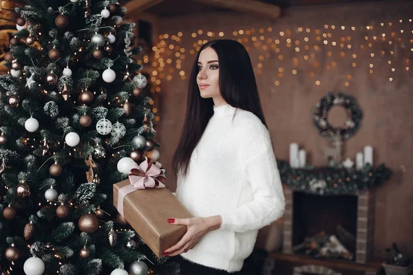 Hermosa mujer con el pelo largo y oscuro en suéter blanco sostiene regalo de Navidad . — Foto de Stock