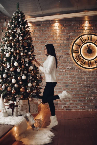 Girl in sweater decorating Christmas tree at home. — Stock Photo, Image