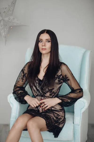 黒のドレスと肘掛け椅子にハイヒールでゴージャスなブルネットのモデル. — ストック写真