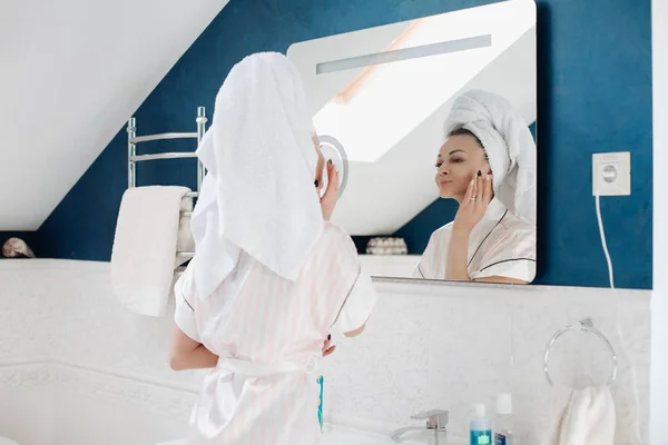 욕실에서 그녀의 얼굴에 크림을 적용 하는 아름 다운 젊은 여자. — 스톡 사진