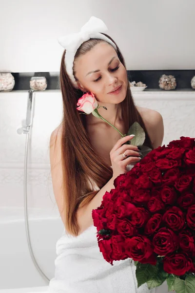 Приваблива жінка в рушнику і пов'язці з букетом червоних троянд . — стокове фото