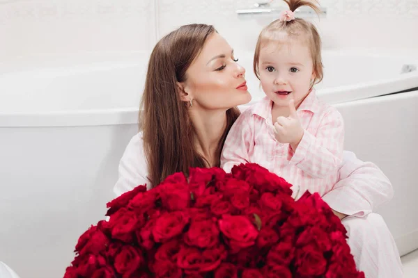 Mooie moeder poseren met meisje en grote boeket rozen — Stockfoto