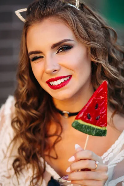 Portret pozytywny Seksowny brunetka z czerwone usta gospodarstwa candy. — Zdjęcie stockowe