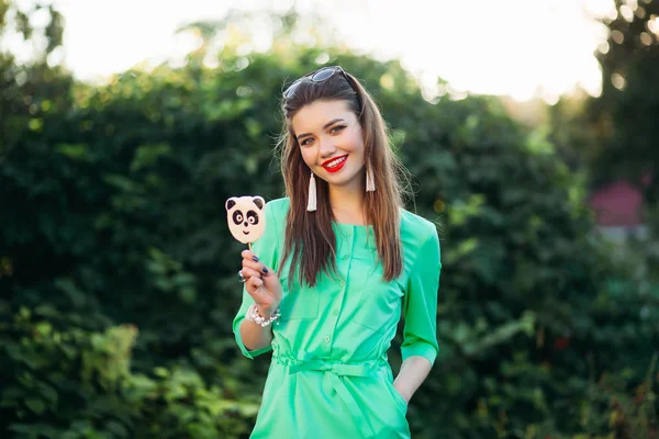 손에 막대기에 사탕과 녹색 드레스에서 소녀 미소의 초상화. — 스톡 사진