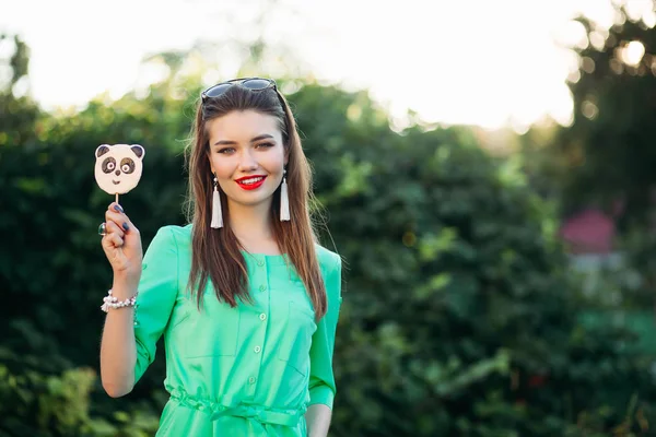 Porträt eines lächelnden Mädchens in grünem Kleid mit Süßigkeiten in der Hand. — Stockfoto