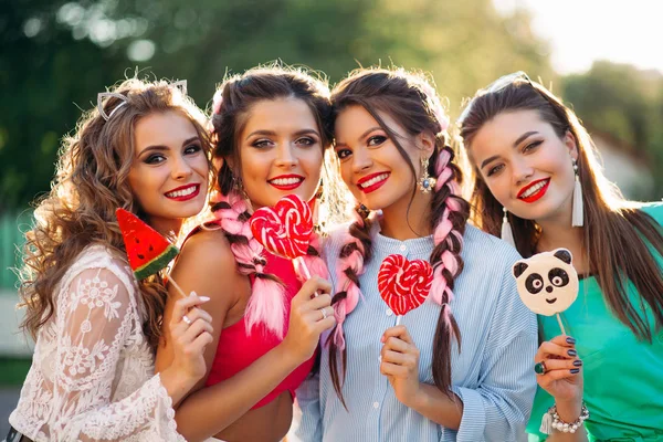 Gruppo di ragazze alla moda con cuori di caramelle su bastone . — Foto Stock