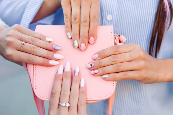 Twee meisjes met ontwerp manicure holding leerzak roze. — Stockfoto