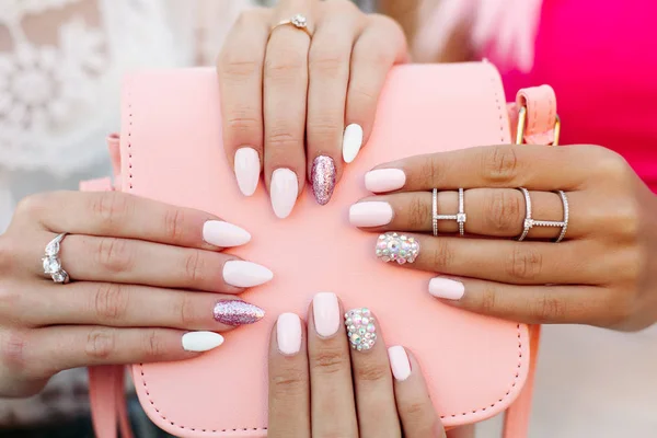 Duas meninas com manicure design segurando saco de couro rosa . — Fotografia de Stock