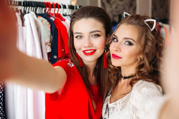 Dos chicas sosteniendo la cámara y tomando autorretrato en la tienda . — Foto de Stock