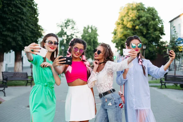 Cuatro mejores amigas de moda y magníficas con gafas, cada una posando haciendo selfies para redes sociales, se divierten. Mujeres en gafas de sol después de ir de compras y salón de belleza — Foto de Stock