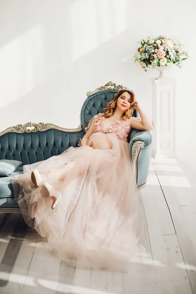 Έγκυος γυναίκα που κάθεται στο μεγάλο διακοσμημένο στεφάνι αμπέλου. — Φωτογραφία Αρχείου