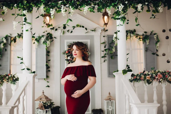 Encantadora mujer embarazada en vestido de marsala posando en los escalones de la casa . — Foto de Stock