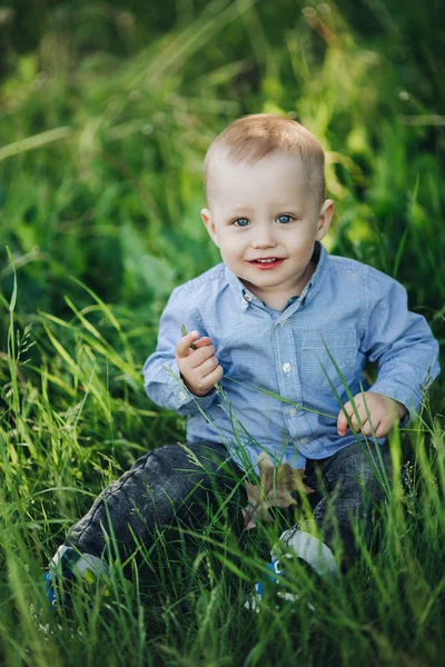 时尚的金发小男孩的肖像坐在公园里的草地. — 图库照片