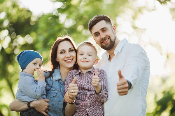 Positive and stylish family gesturing super by fingers at camera.