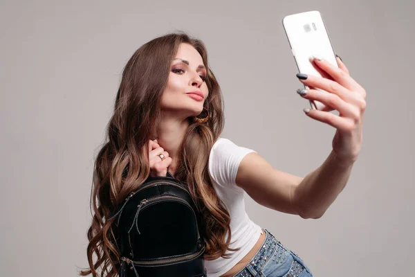 Young girl with trendy backpack doing selfie on phone — Stock Photo, Image