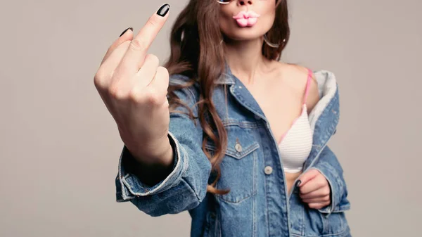 Aggressive girl in stylish sunglasses with pink plump lips showing fuck at camera. — Stock Photo, Image