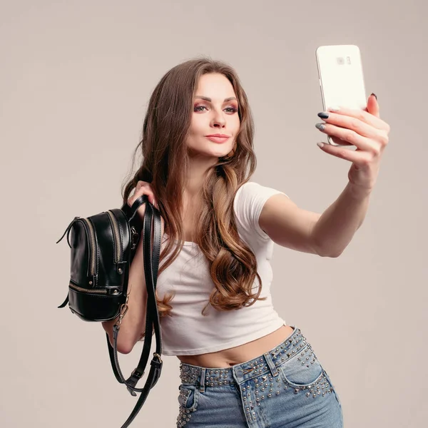 Pretty lady in white t-shirt and jeans looking at herself. — Stock Photo, Image