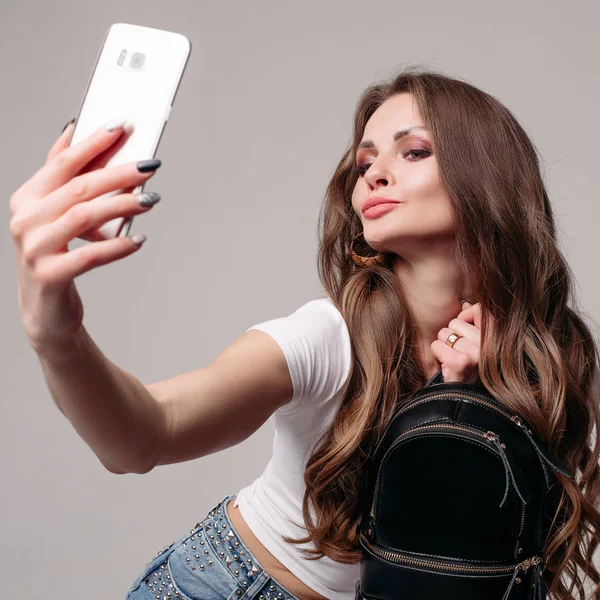 Young girl with trendy backpack doing selfie on phone — Stock Photo, Image