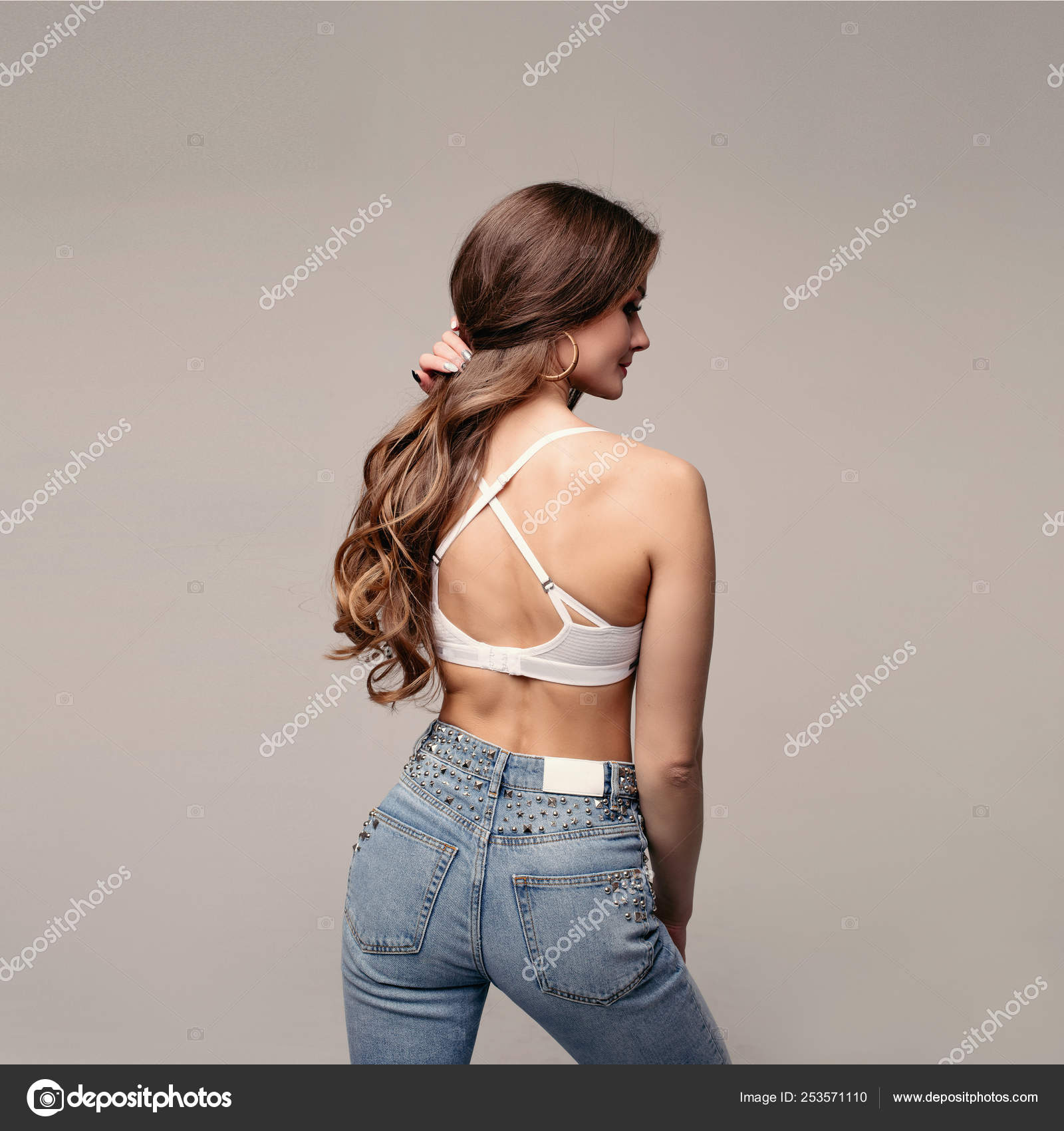 Brunette slim model in jeans and sports bra. Stock Photo by