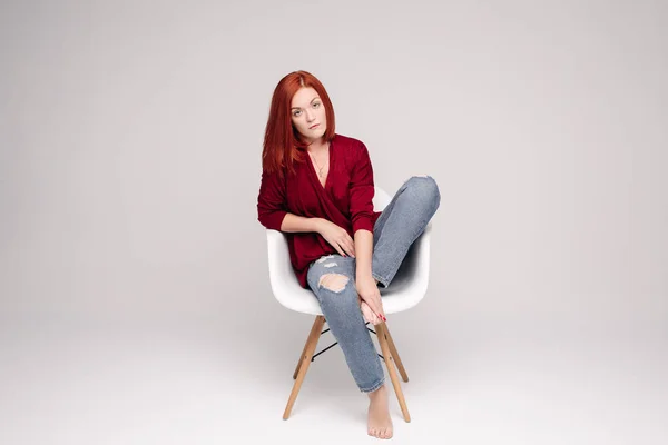 Modelo com cabelo de gengibre sentado na cadeira branca em estúdio . — Fotografia de Stock