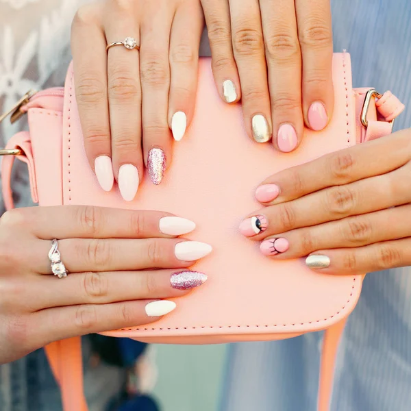 Duas meninas com manicure design segurando saco de couro rosa . — Fotografia de Stock