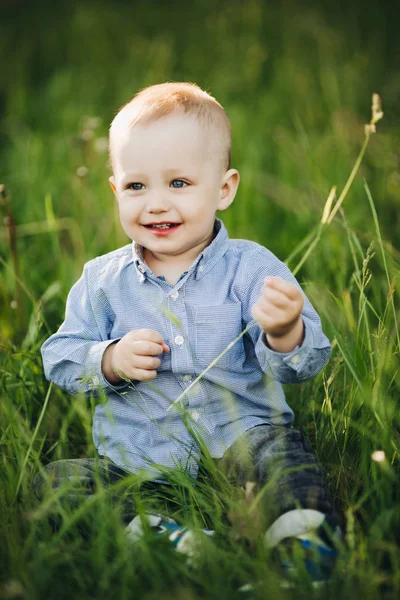 时尚的金发小男孩的肖像坐在公园里的草地. — 图库照片