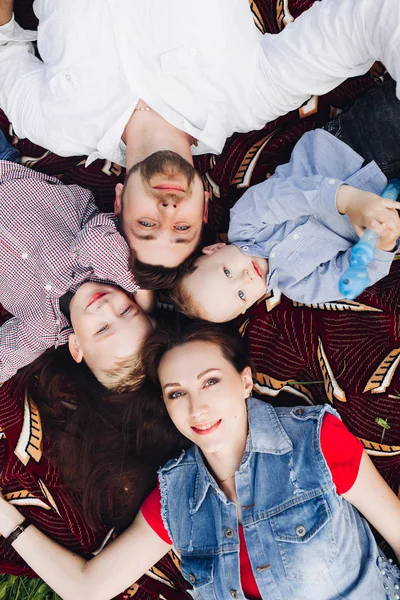 Above view of happy family lying in park together with kids and smiling. Stock Picture