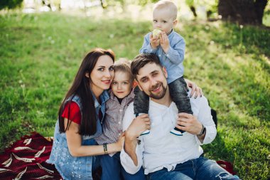 Mutlu aile ile birlikte kucaklayan çocuklar, parkta oturan.