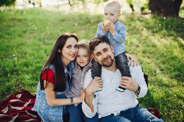 Щаслива сім'я сидить у парку разом з дітьми, обіймаючи . — стокове фото