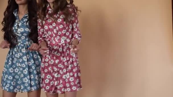 Två lyckliga tjejer som bär ljus klänningar dansar — Stockvideo