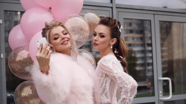 Två vackra och sexiga flickvänner tar selfies med Luftballonger. — Stockvideo
