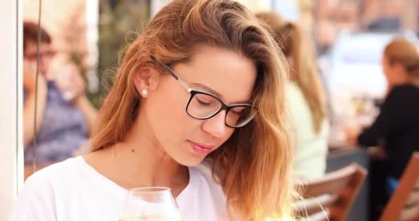 Chica bastante joven en gafas de navegación por la red en la cafetería al aire libre . — Vídeos de Stock
