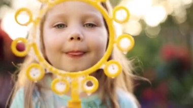 Süper sevimli adil saçlı küçük kız t-shirt çim sabun kabarcıkları üfleme.