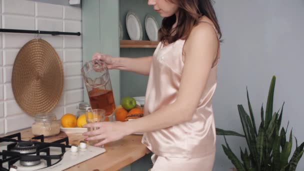 Fiatal lány pizsamában, friss gyümölcslevet iszik reggel. — Stock videók