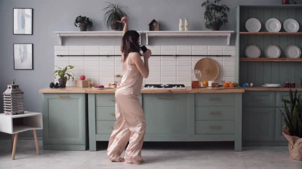 穿着睡衣的女人在家厨房里跳舞唱歌 — 图库视频影像