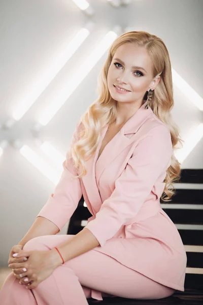 Blondin i rosa Smart kostym sitter på trappor och poserar — Stockfoto