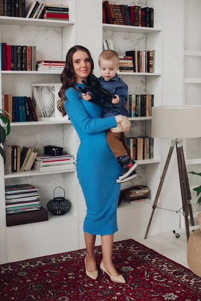 Gorgeous kärleksfull mamma i blå klänning med sin son i vardagsrummet. — Stockfoto