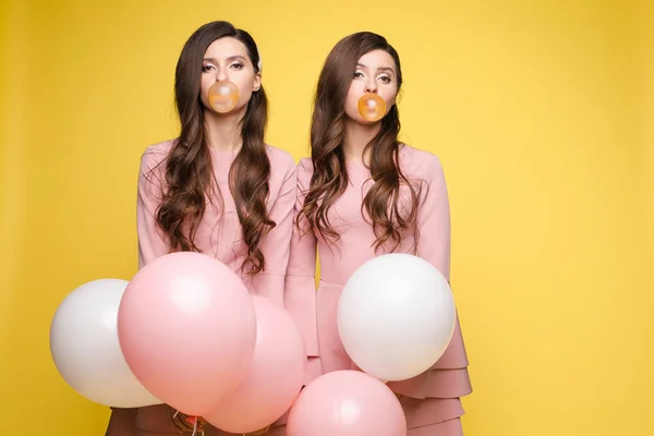 Giovani gemelli che tengono in mano palloncini rosa e bianchi . — Foto Stock