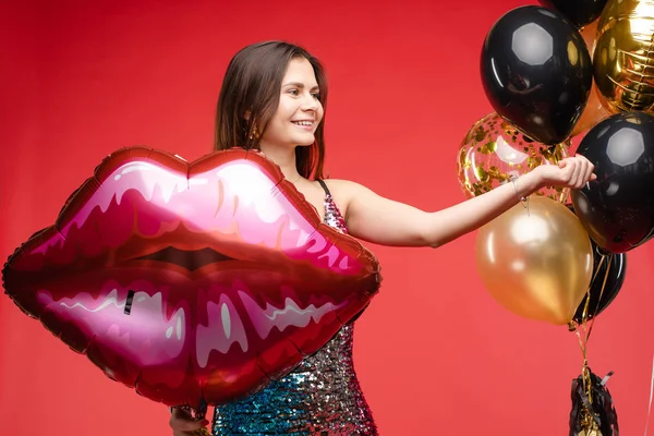 Sexy elegante Brünette in wunderschönem funkelnden Kleid mit Luftballons. — Stockfoto