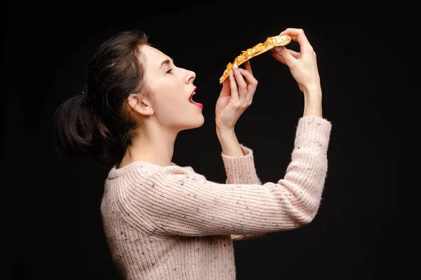 Młoda biała kobieta z ogonem jedząca kawałek pizzy. — Zdjęcie stockowe