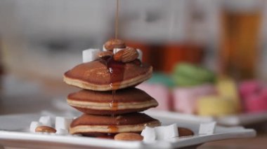 Kahvaltı. Şurup krep güzel ve yavaş dökülür. Yavaş çekim. Parlak bulanık arka plan. Lezzetli ve iştah açıcı. Tatlı gözleme akçaağaç şurubu dökün