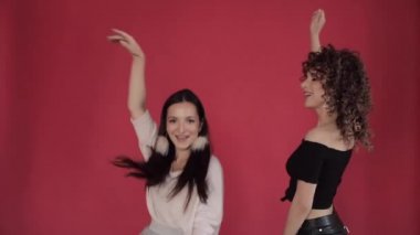 Stüdyoda kırmızı arka plan aleyhine dans ve şarkı iki mutlu arkadaş.