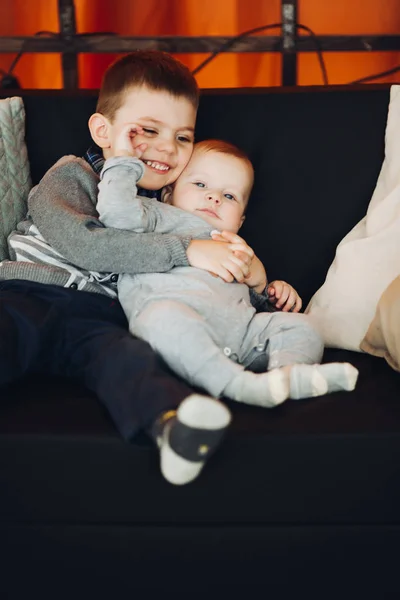Gelukkige jongen omarmen zijn kleine broertje. — Stockfoto